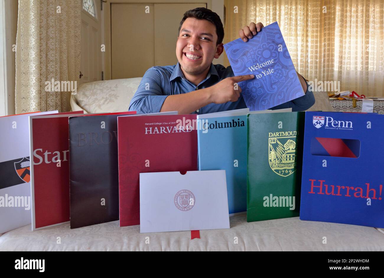 In this June 1, 2015 photo, Fernando Rojas, 17, a Fullerton High School  graduate, poses for a photo in Fullerton, Calif. with literature from the  eight Ivy League universities he was accepted