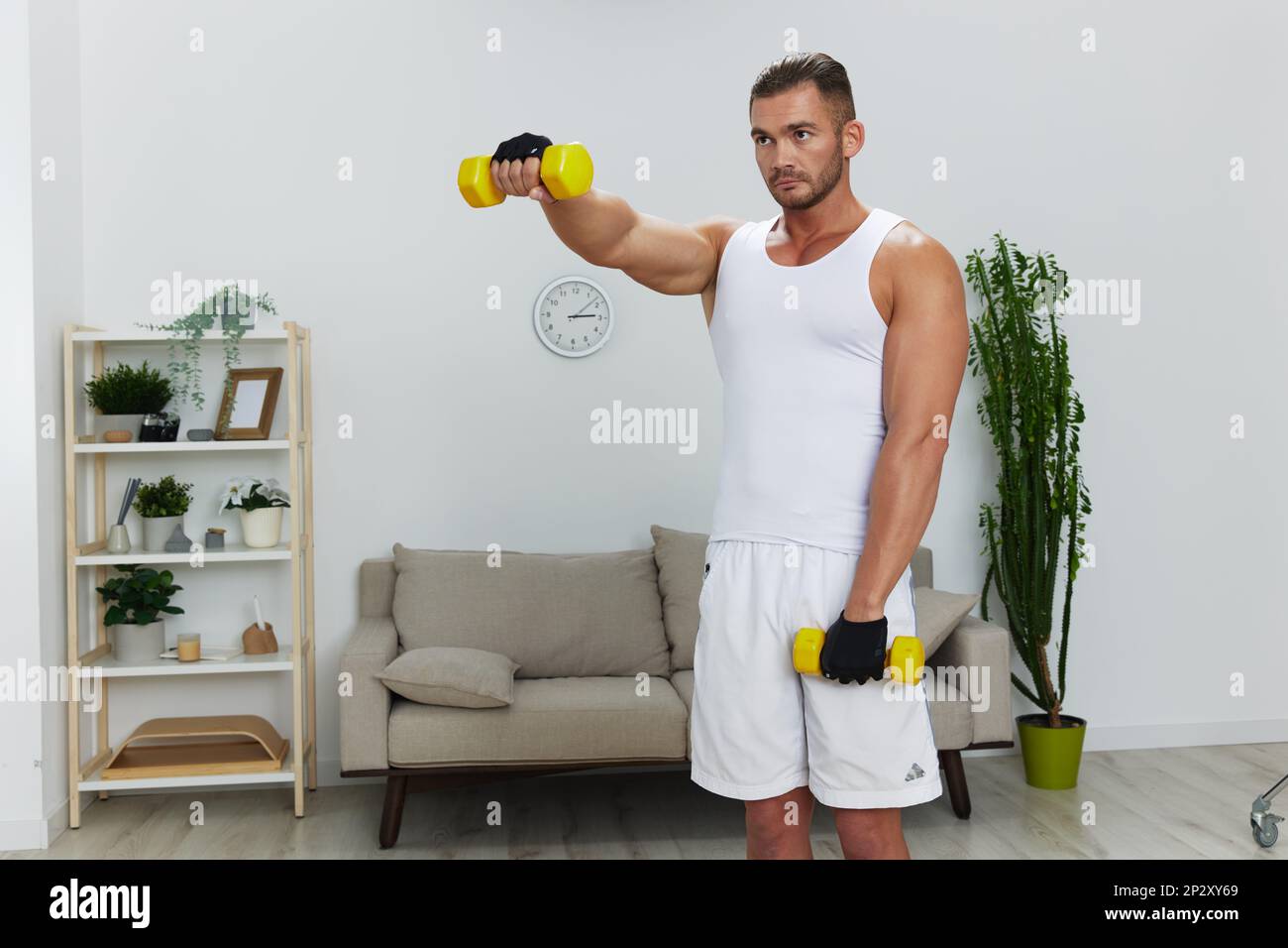 Man sports home training on the floor on a mat with dumbbells