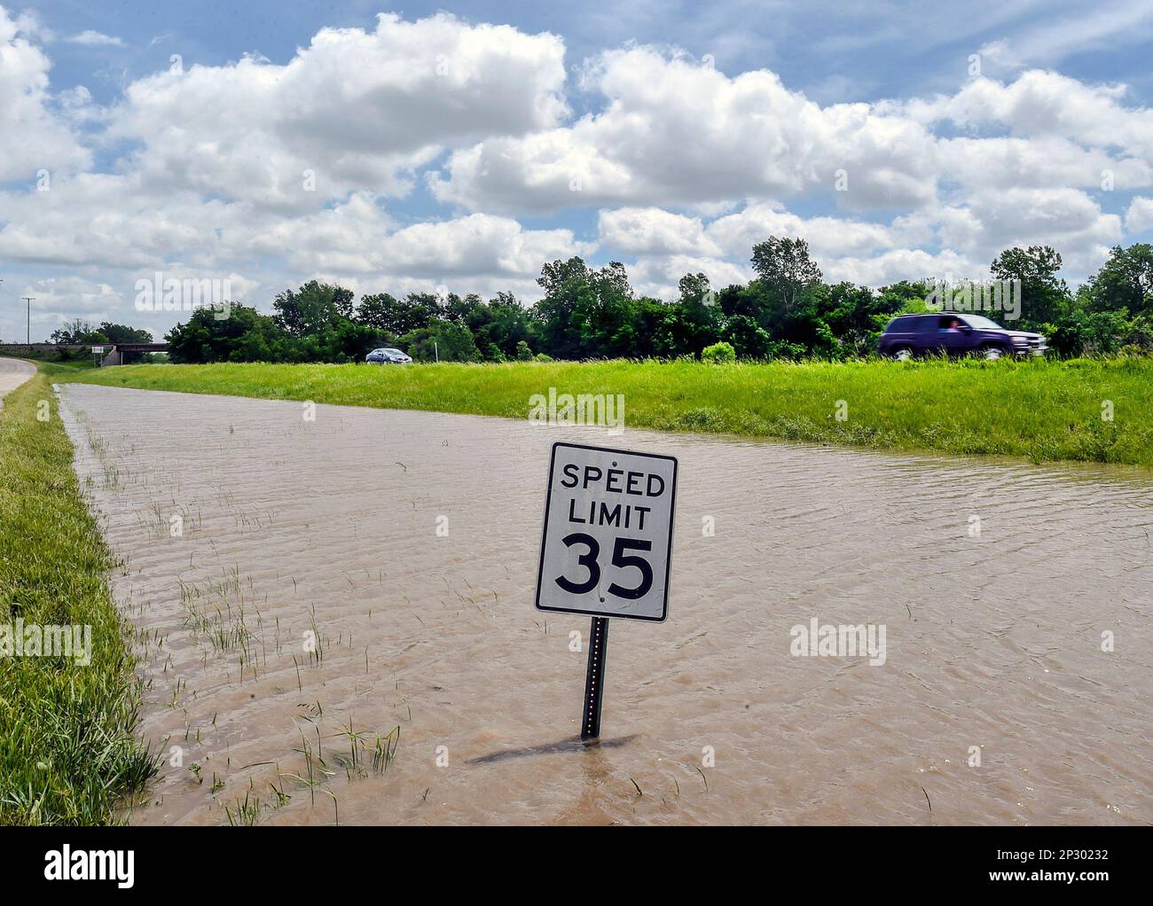 Cars pass flood waters on U.S. 69 on Sunday, May 17, 2015, in Mosby, Mo