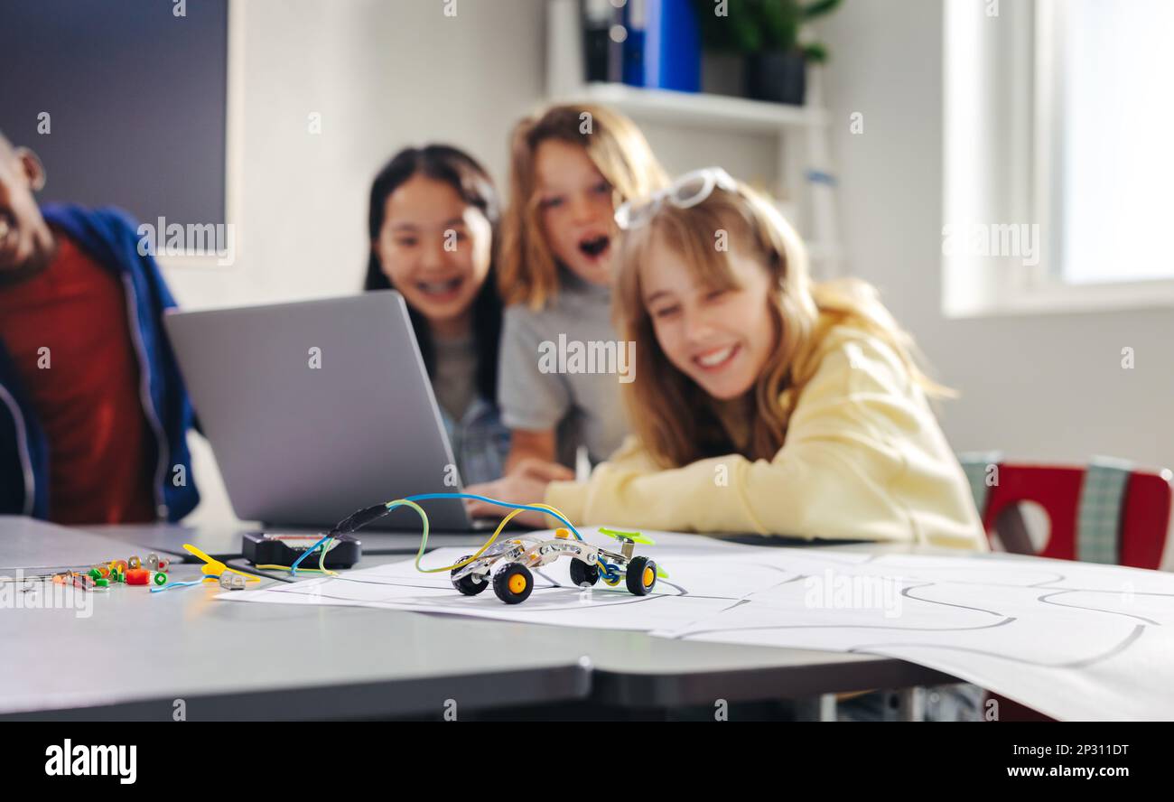 Practical robot programming lesson for children using a laptop to control their creations. Primary school kids learning the basics of coding as they p Stock Photo