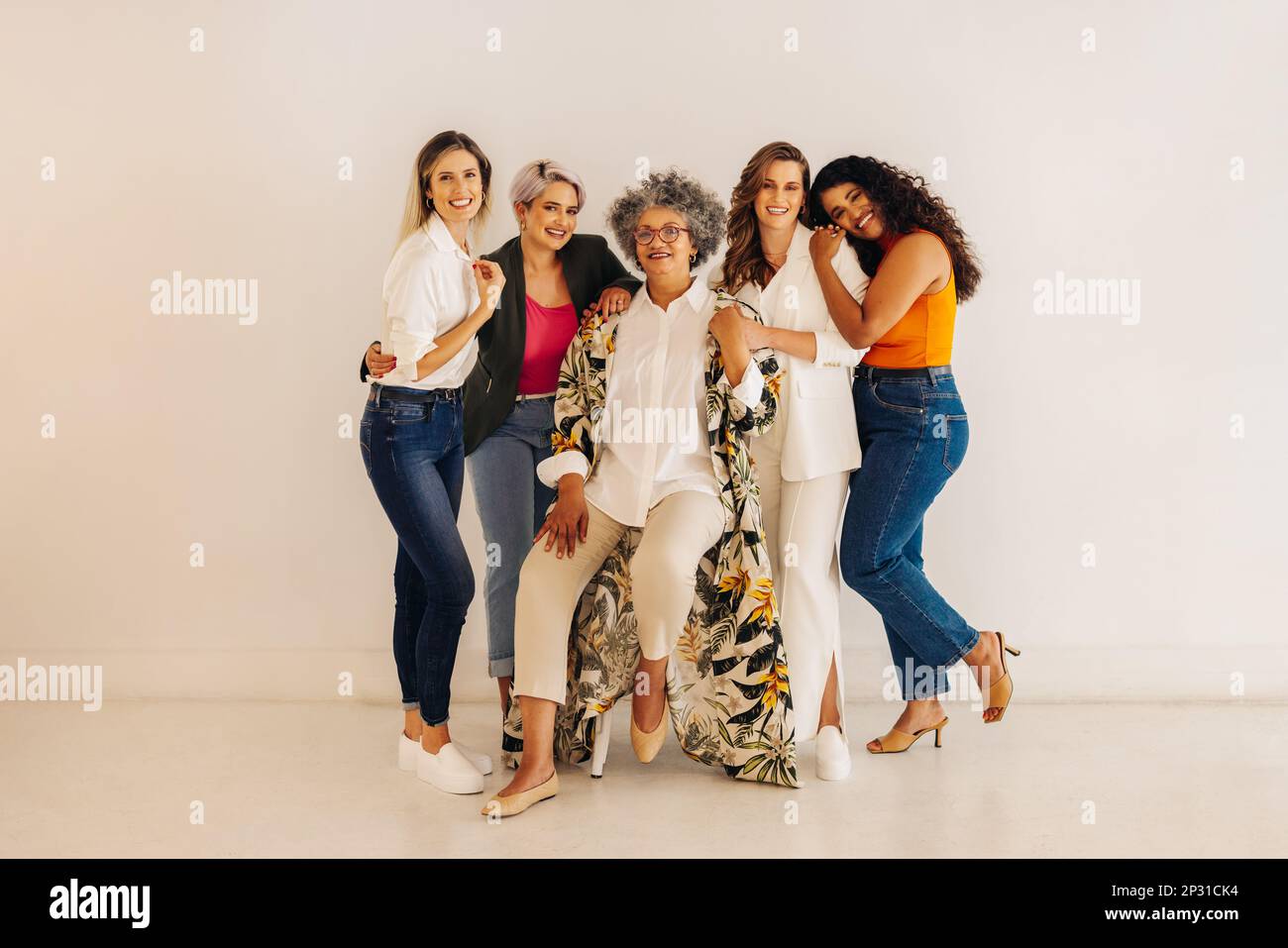 Woman-owned startup. Multicultural businesswomen smiling at the camera while standing together against a wall. Group of successful businesswomen worki Stock Photo