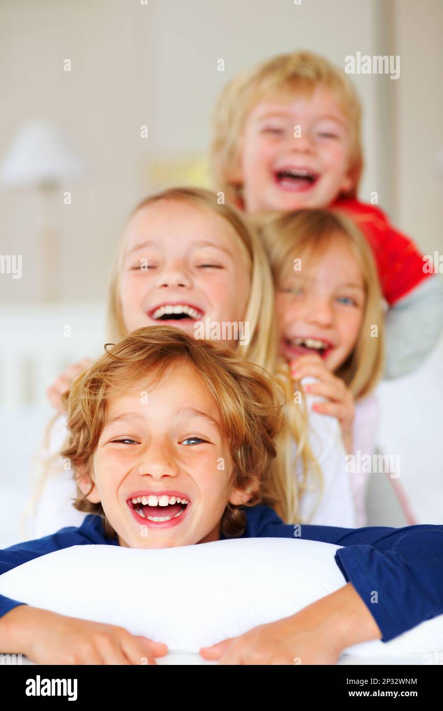 Joyful little brothers and sisters having fun in bed. Portrait of joyful little brothers and
