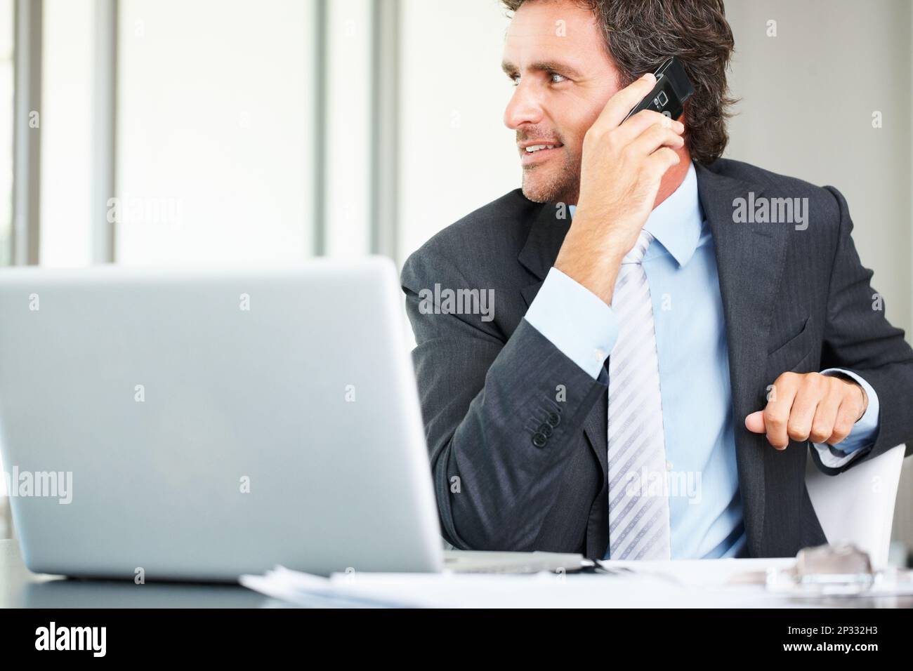 Business man using cell phone and laptop. Smart middle aged business man using cell phone and laptop. Stock Photo