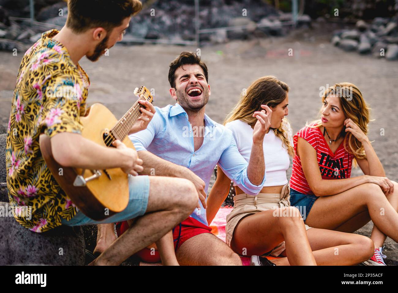 Four friends gather on a beach by the sea, with two men and two women  sitting