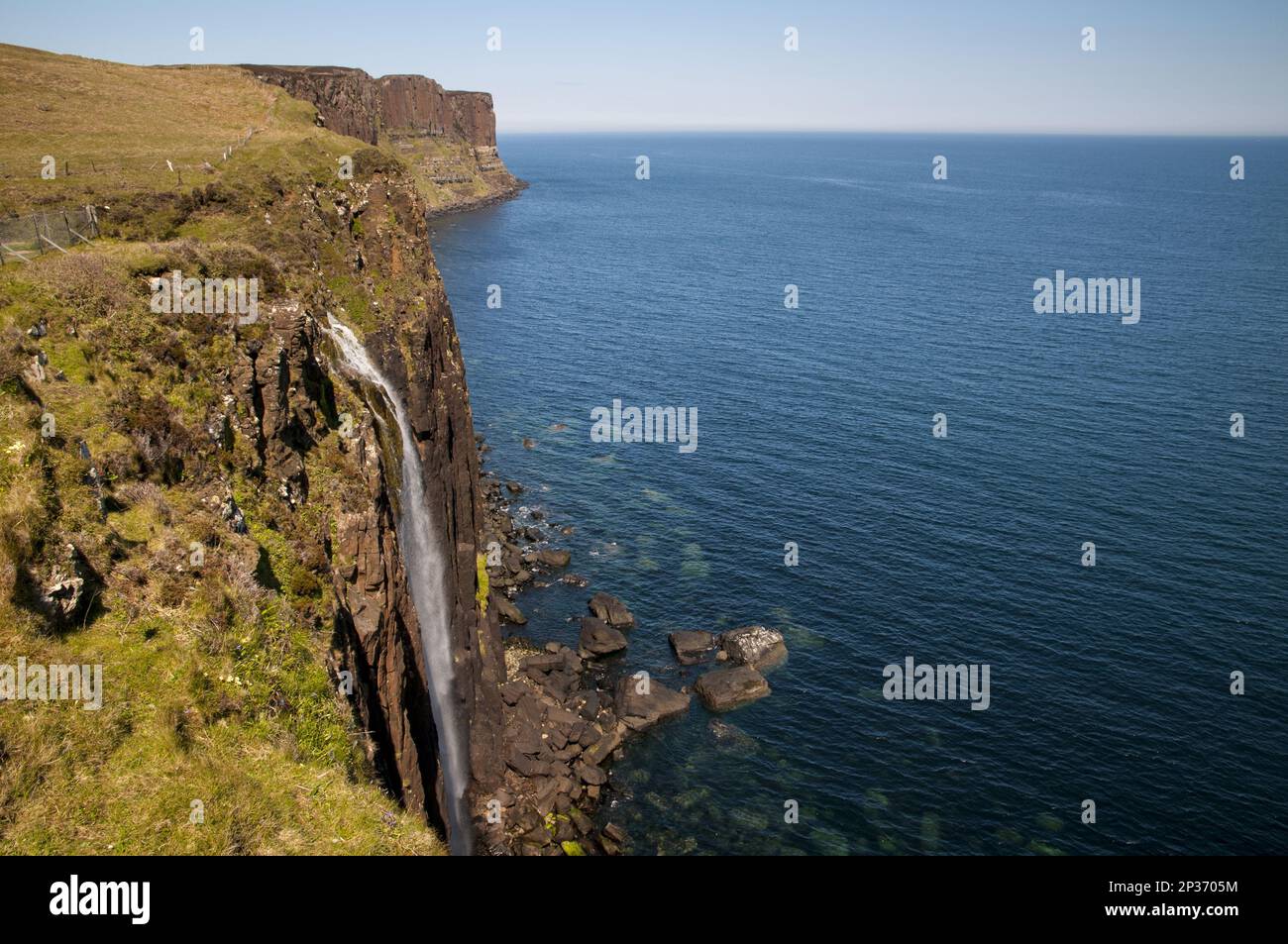 View of the coastline with a waterfall cascading over cliffs into the ...