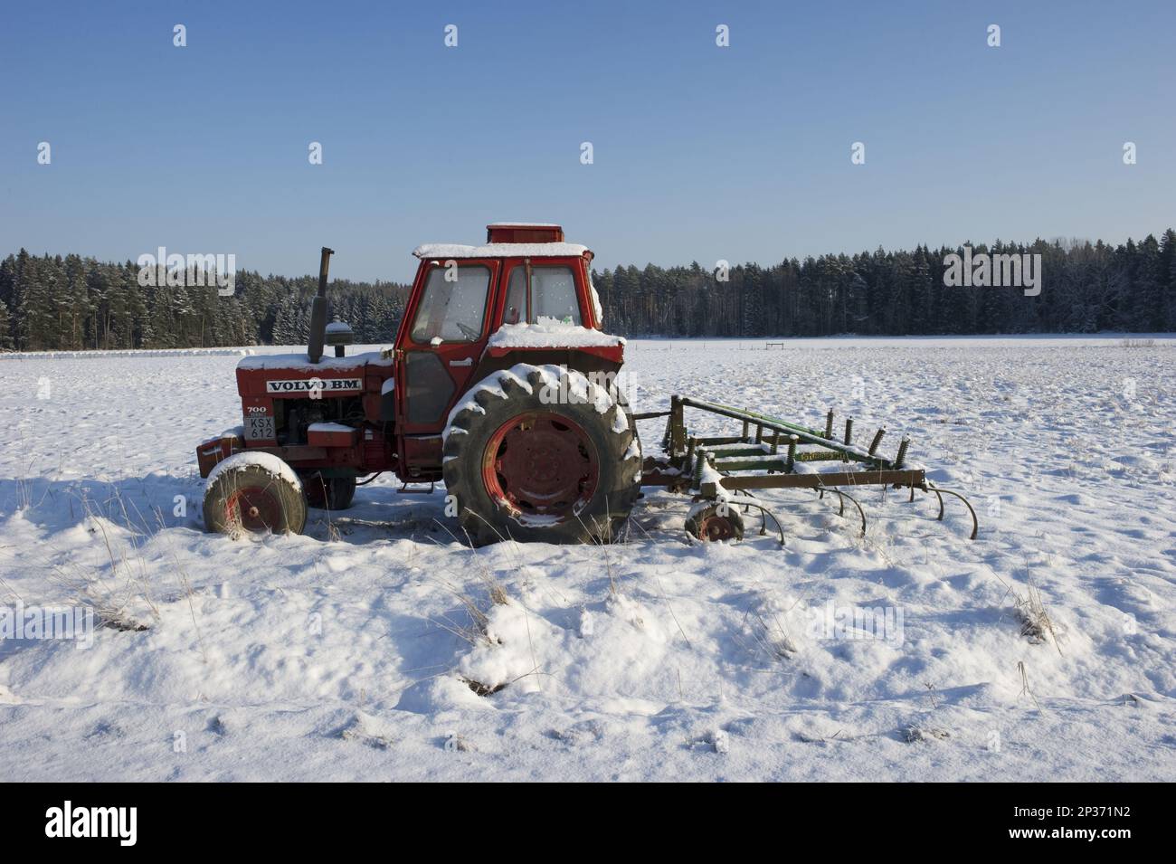 Volvo BM 700 tractor and spring tooth harrow covered with snow, Sweden Stock Photo