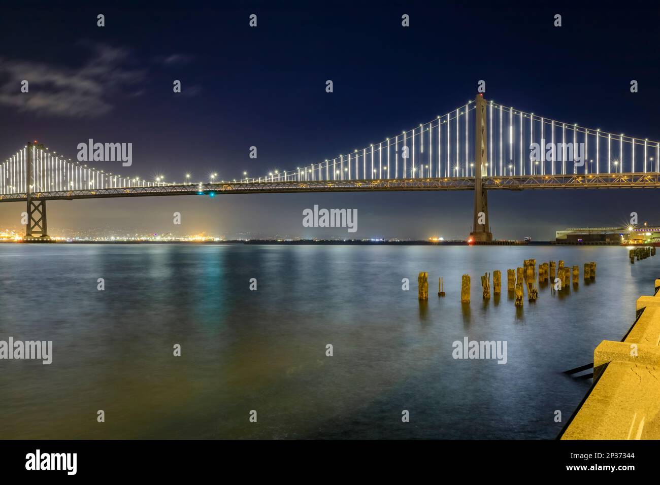 San Francisco Bay Bridge lights at night, reflecting of the water in