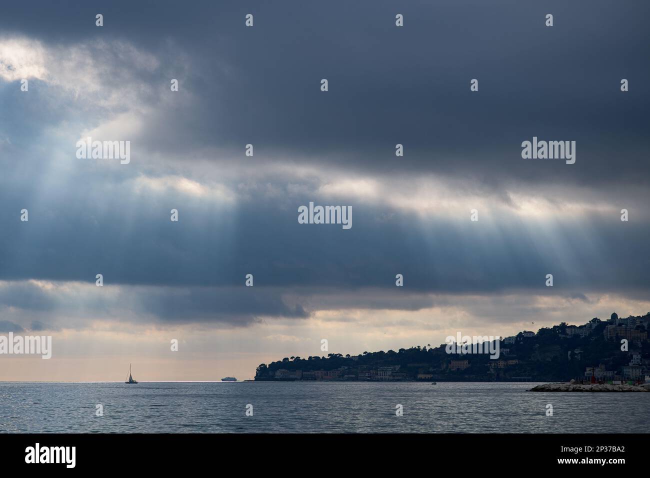 Sunrays through the clouds over the Naples bay in the Mediterranean sea ...