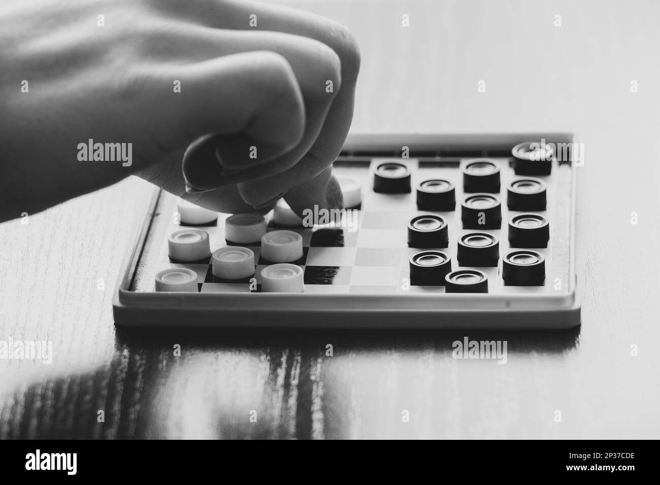 Board small old game checkers on the table and a woman's hand , board
