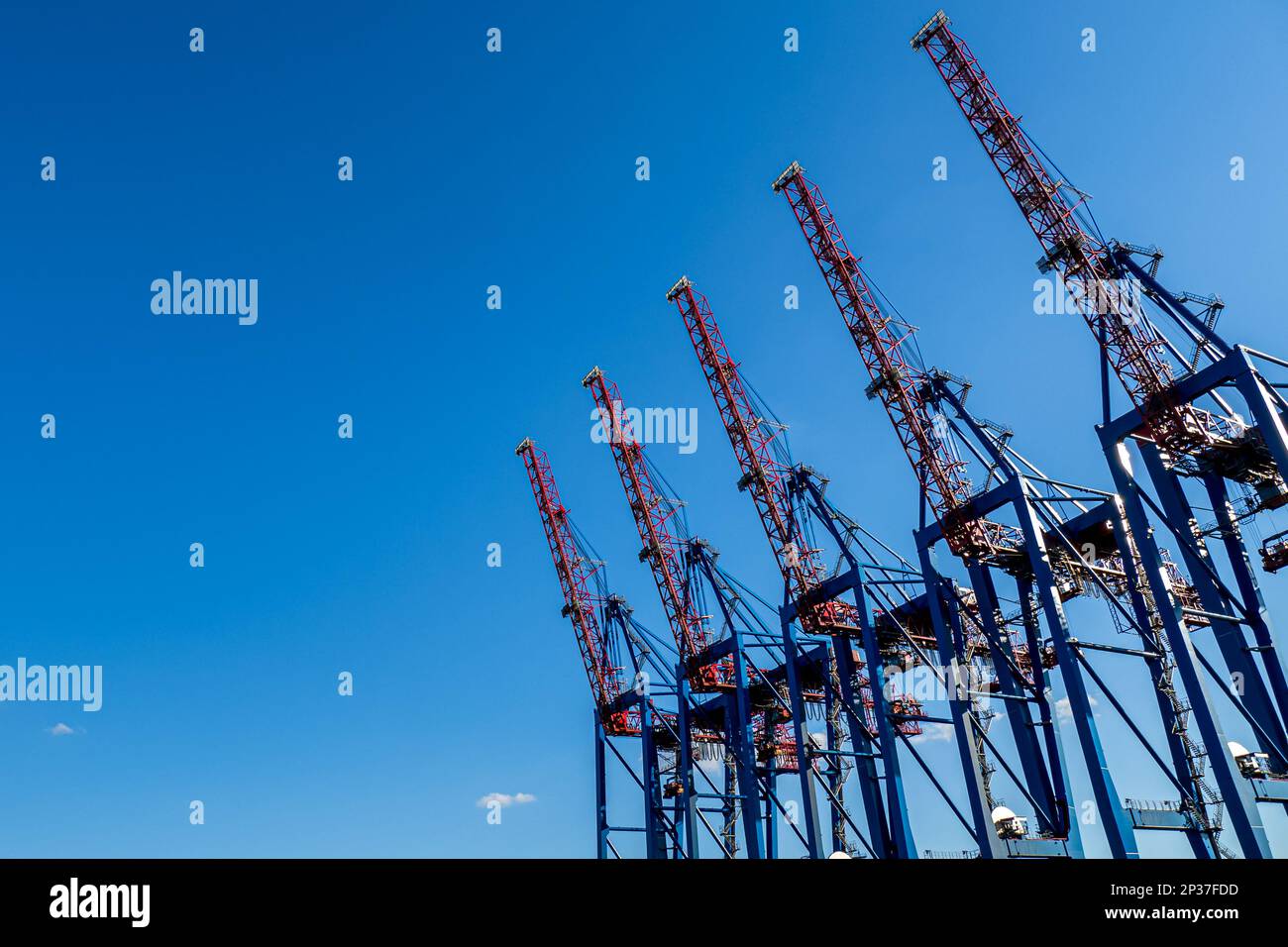 Towering red and blue cranes against blue sky, emphasizing the role of ...
