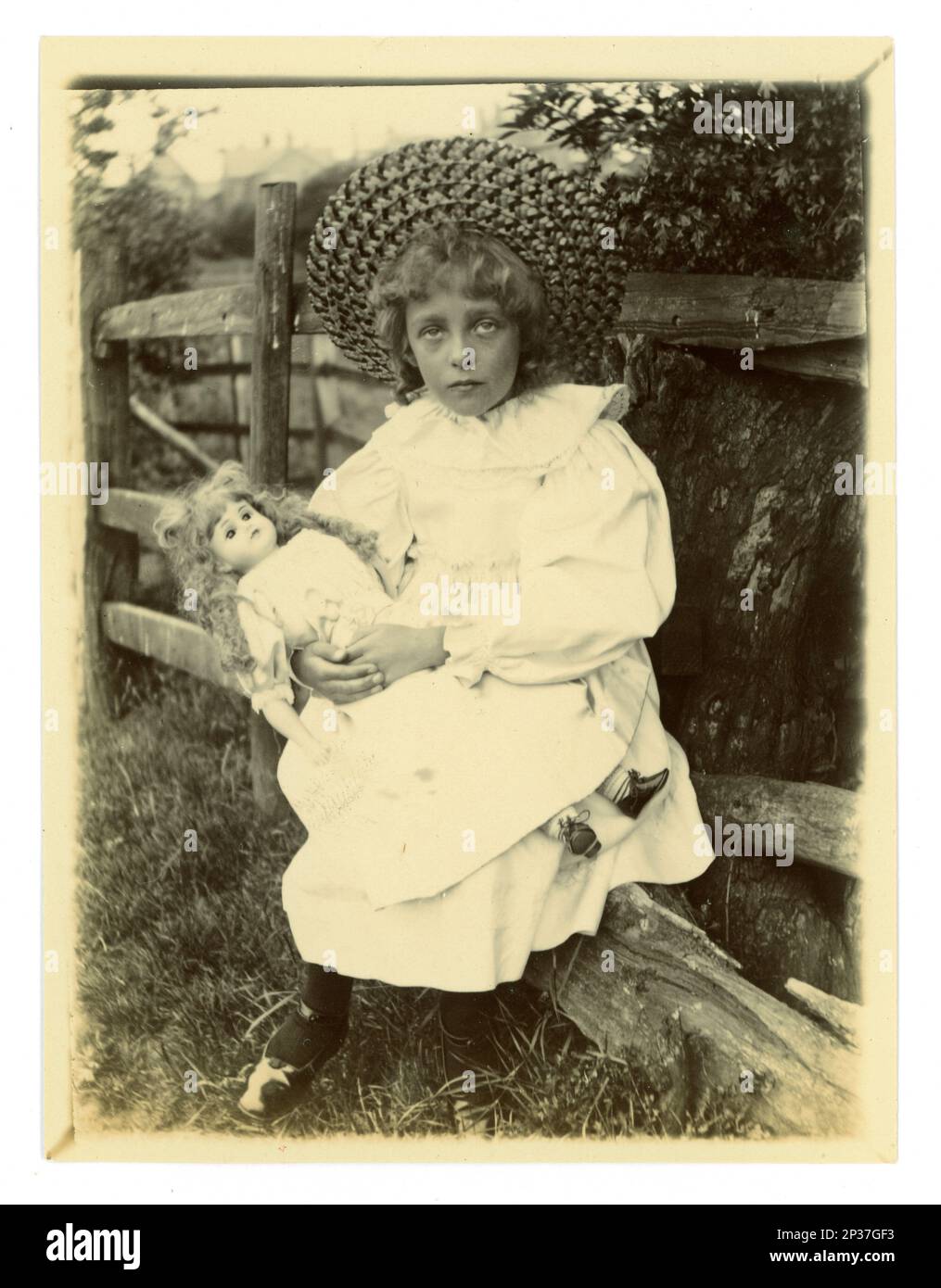 Original Victorian photograph of a young girl with disabilities & a new doll, from a wealthy family sitting outside in a garden, circa 1898, Worcester area, U.K. Stock Photo