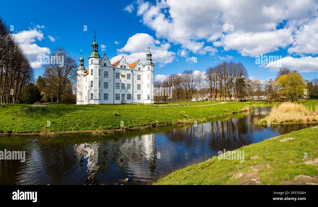 Spring day at the moated white Renaissance castle Schloss Ahrensburg, surrounded by a park and reflected in the tranquil water of the castle moat. Stock Photo