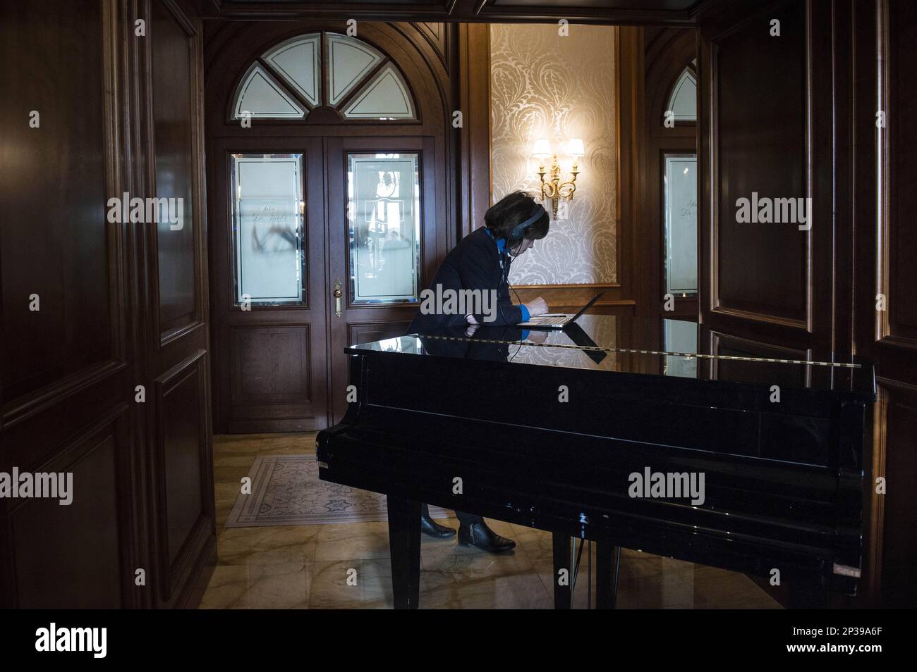 A reporter leans on a piano as she works at the Beau Rivage Palace Hotel in  Lausanne, Switzerland, on Wednesday April 1, 2015, during an extended round  of talks on Iran's nuclear
