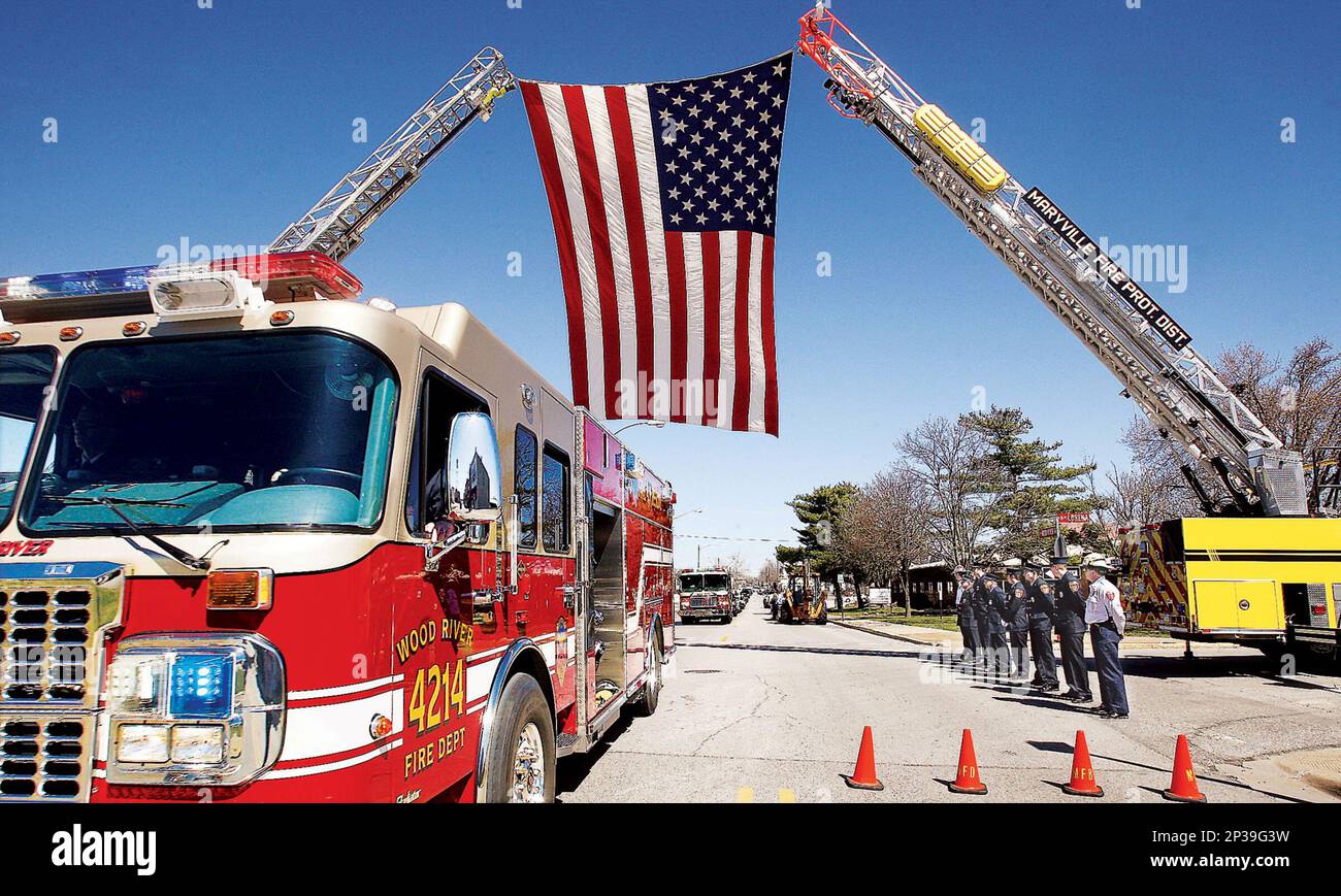Wood River, Ill., fire trucks pass firefighters from the Illinois