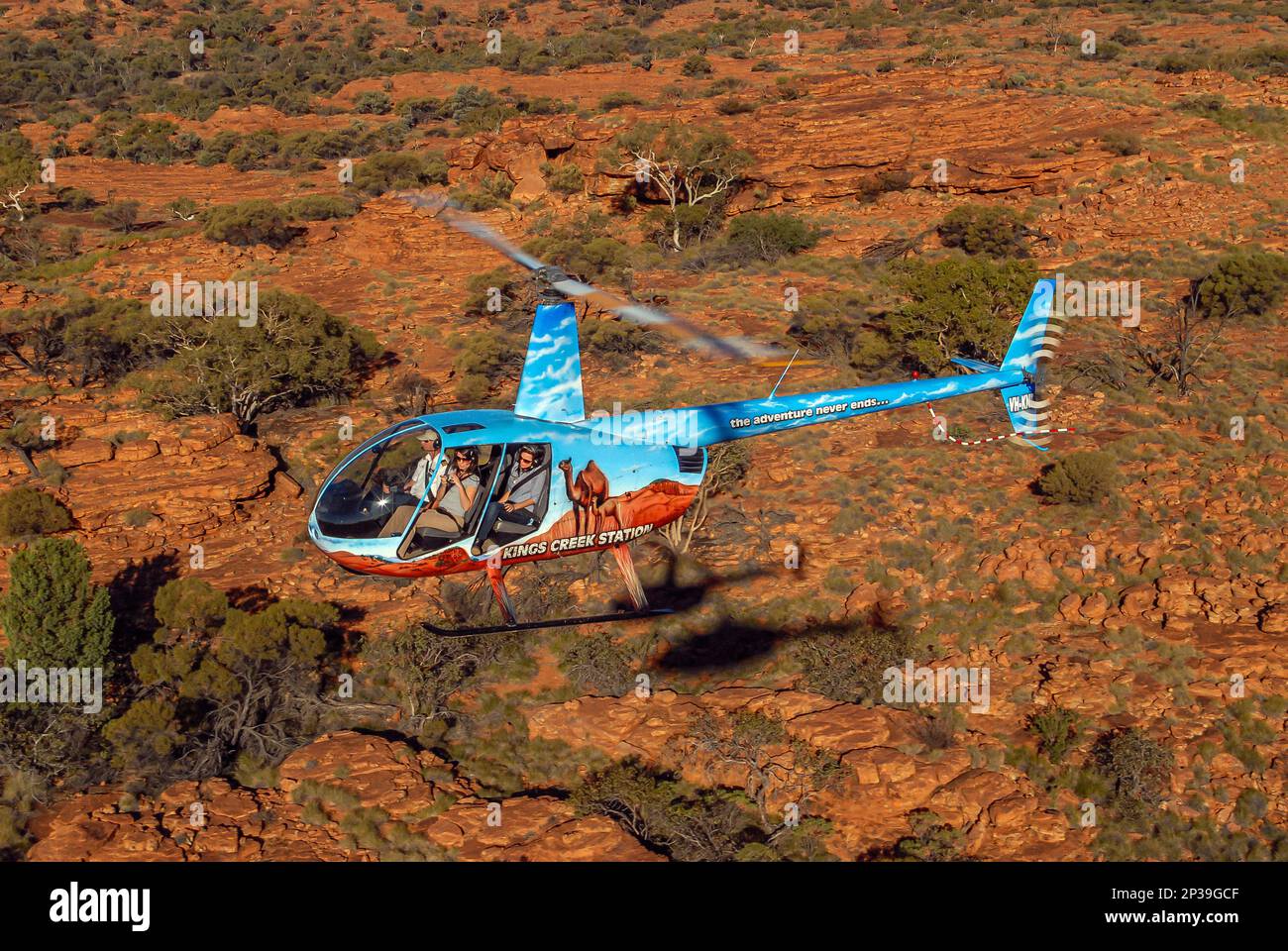 A Robinson R44 Clipper helicopter with open doors, flying tourists over ...