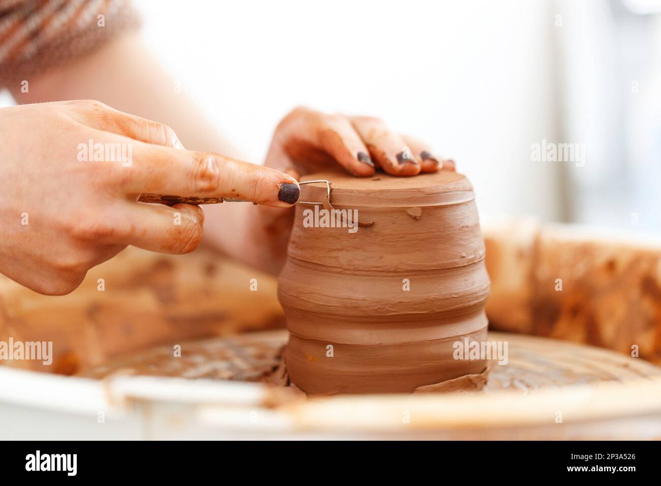 Cropped close up image. Woman's hands molding clay, making a clay pottery in the handicraft workshop. Artisan production earthenware concept. Macro Stock Photo