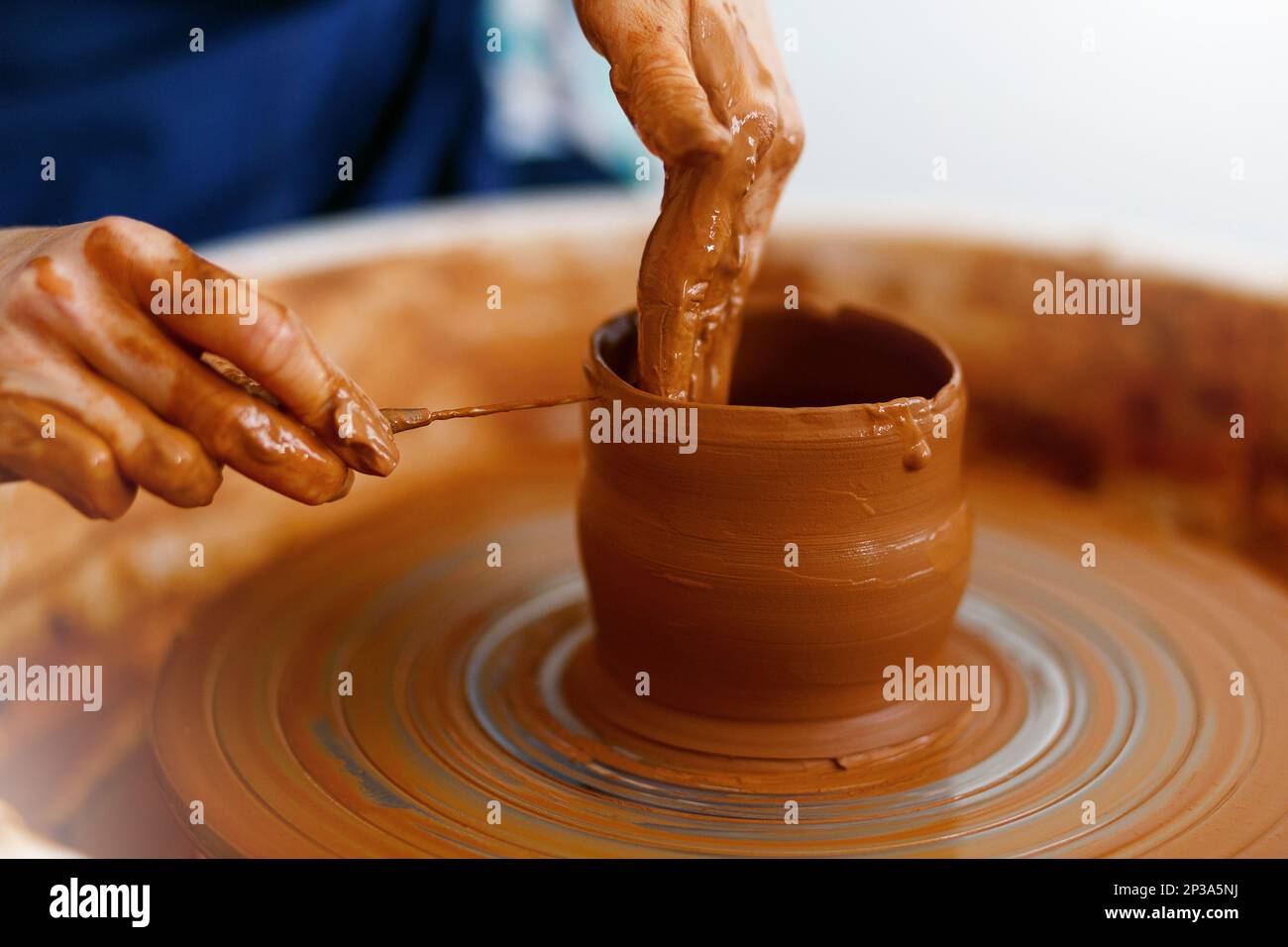 Cropped Image of hands working with Pottery Wheel, close up of shaping clay edges Stock Photo