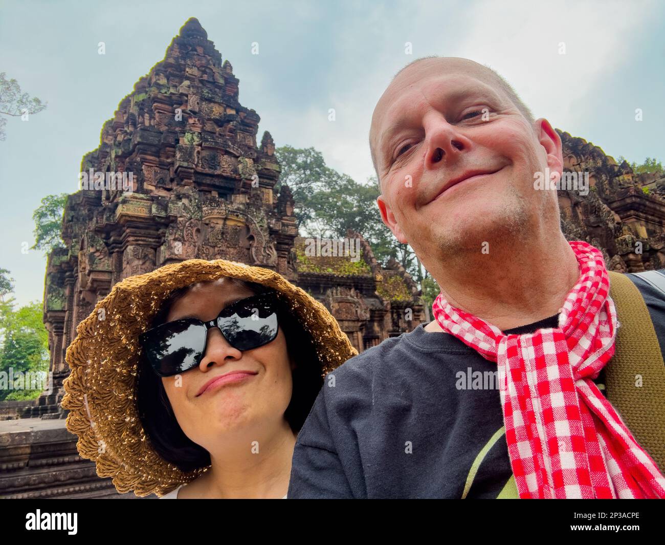 A middle aged couple pose for a selfie at the famed and elaborate Banteay Srey temple at Angkor, near Siem Reap in Cambodia. Stock Photo