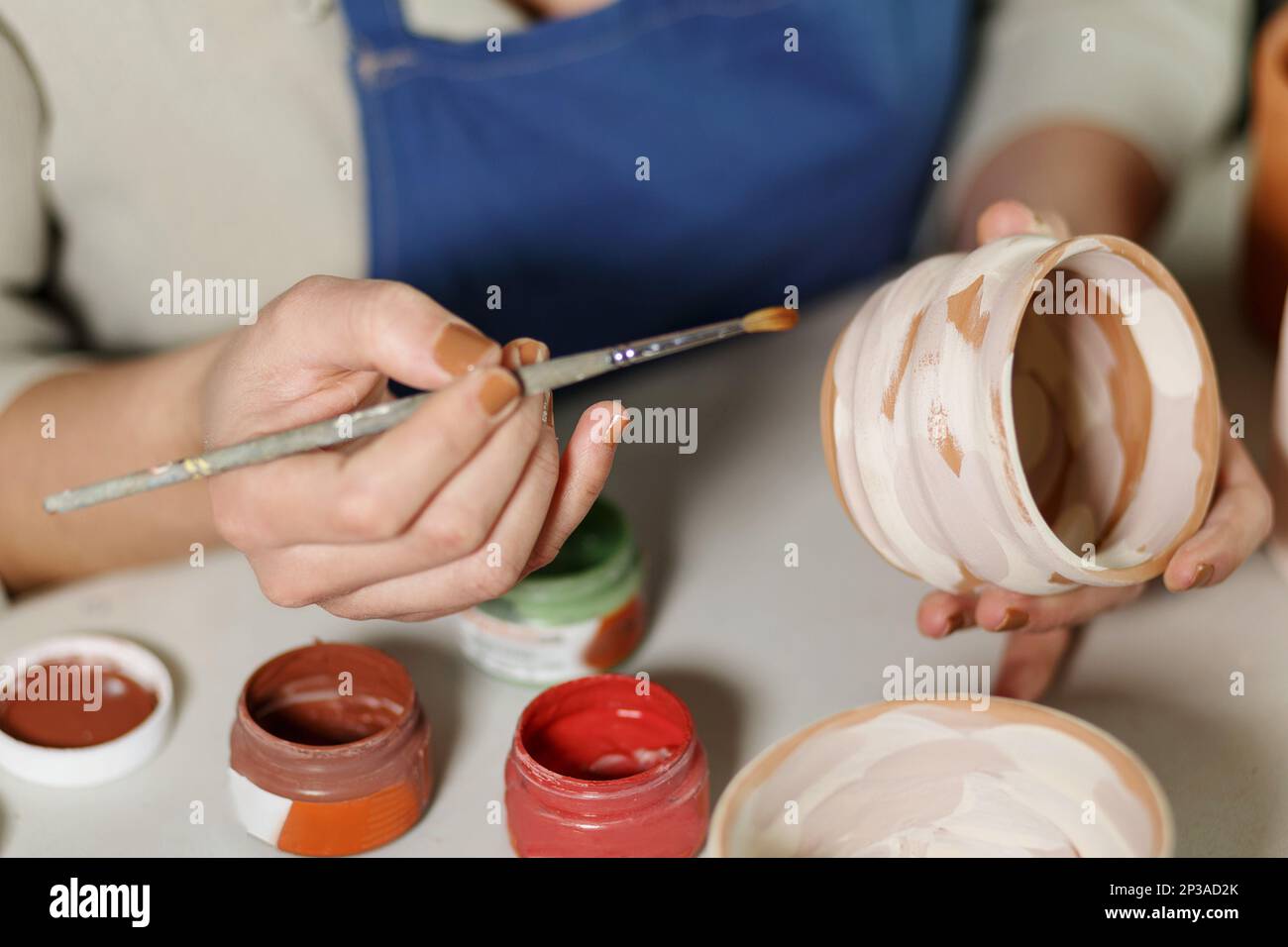 Woman hands, pottery studio and painting cup in workshop for sculpture, creative manufacturing or design. Painter, ceramics product and brush process Stock Photo