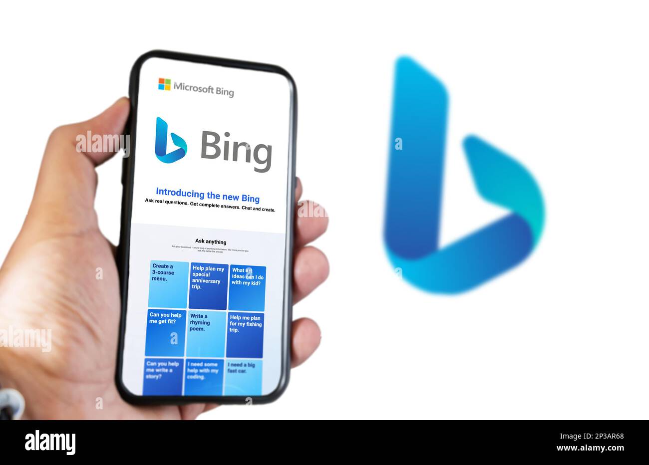 Redmond, US, Feb 2023: A hand holding a phone with the Microsoft Bing website on the screen. White background with blurred Bing logo. Bing is a search Stock Photo