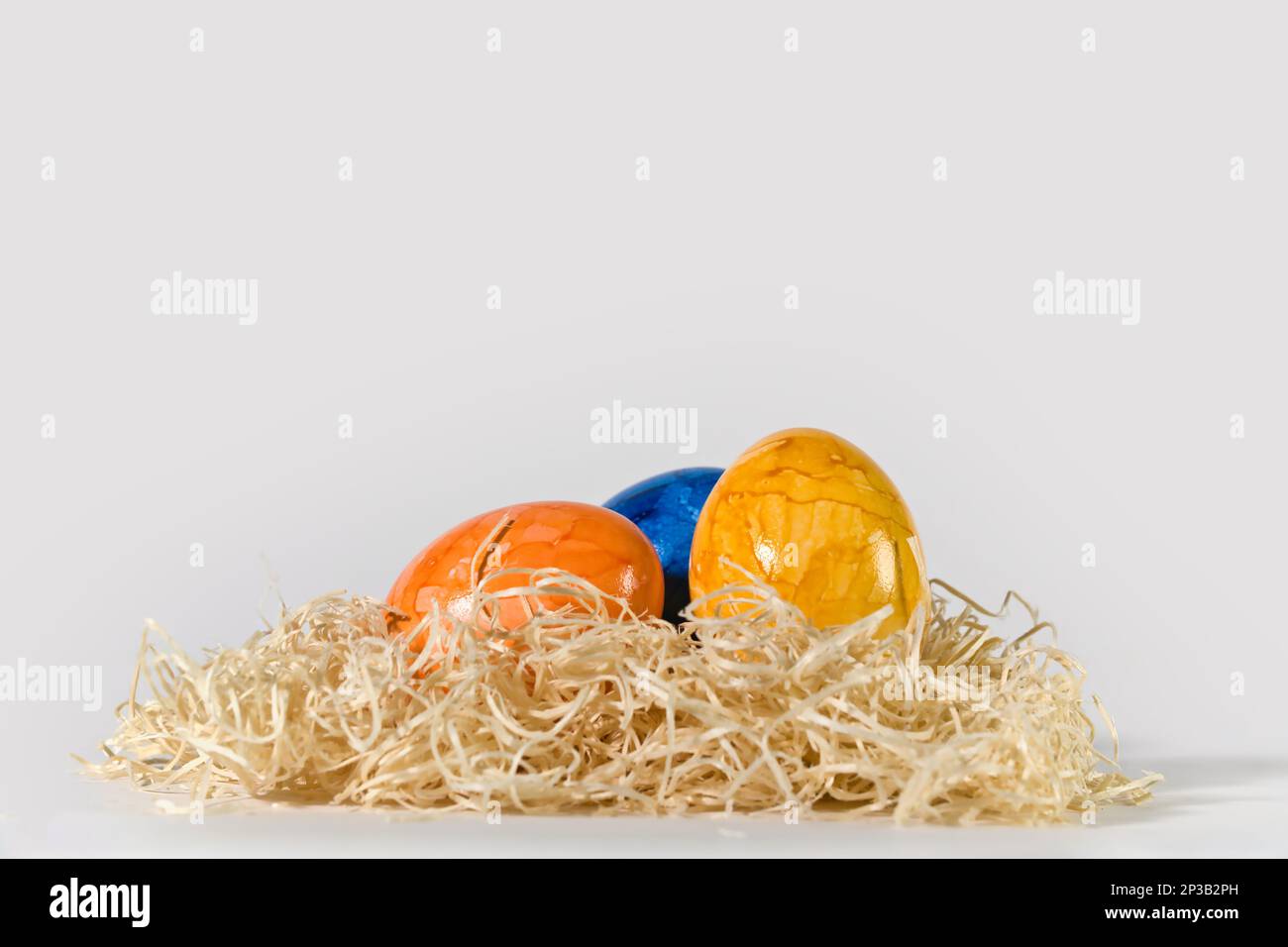 colorful easter eggs in a straw nest, white background Stock Photo - Alamy