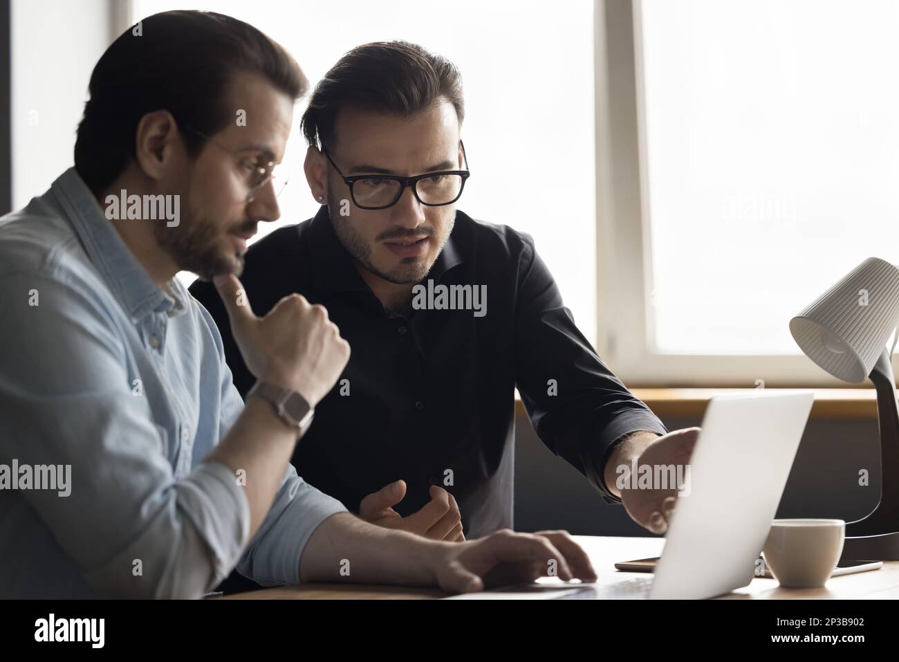 Focused engaged software developers discussing online application Stock Photo