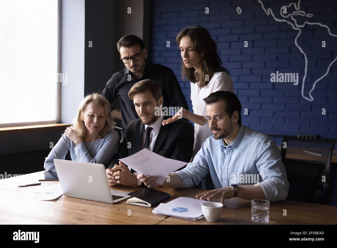 Busy diverse business team sharing computer in modern office together ...