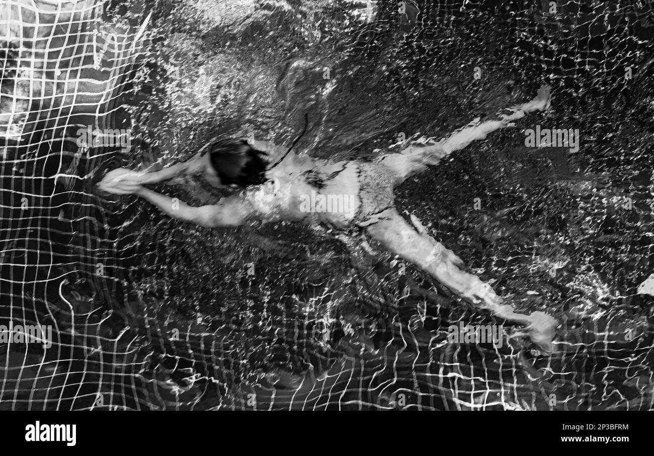 An abstract view of a woman swimming in a pool in Siem Reap in Cambodia. Stock Photo