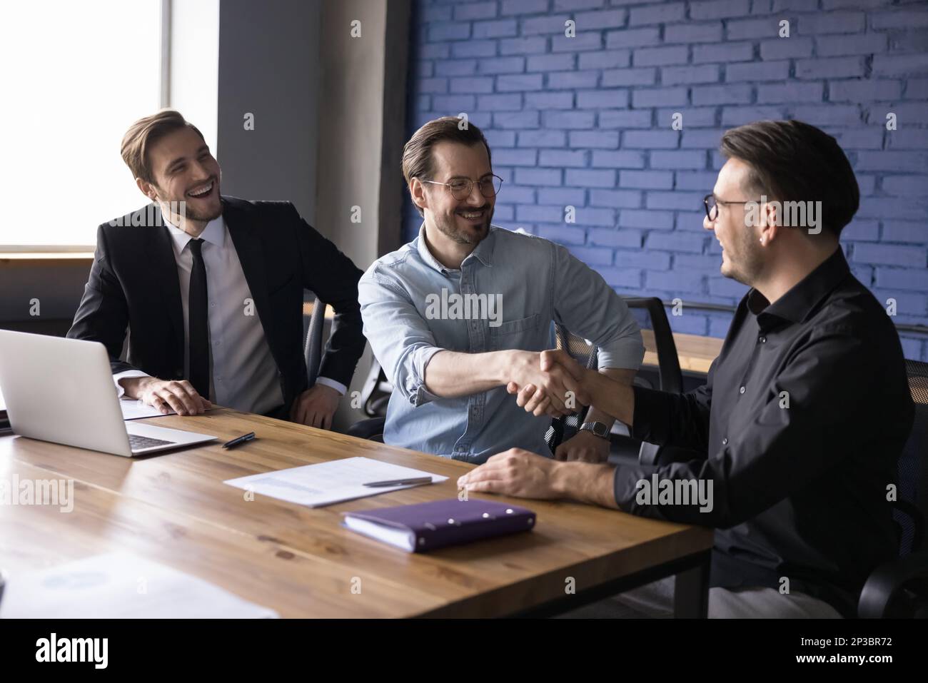 Happy business partner men shaking hands at work office table Stock Photo