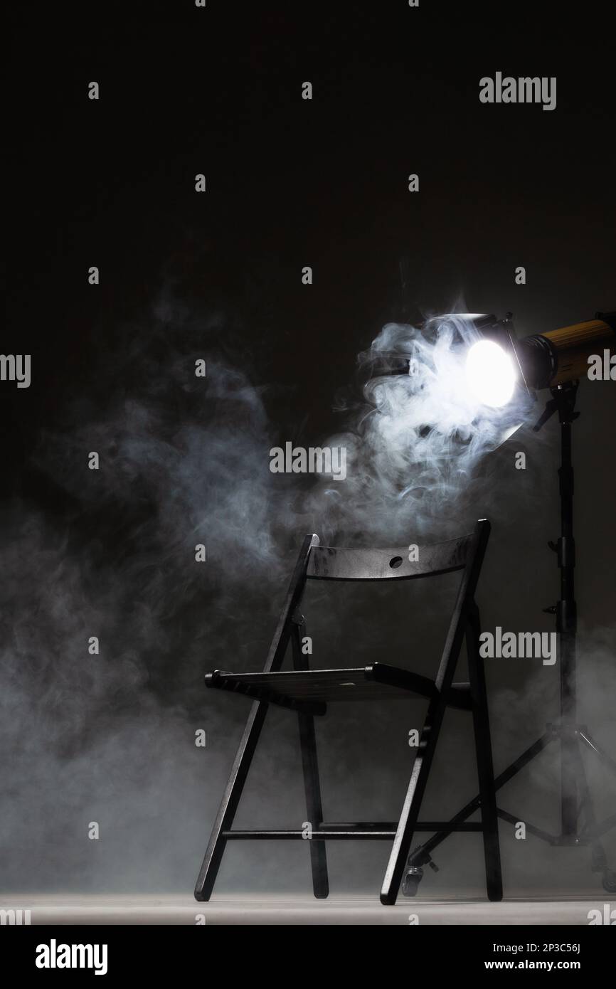Movie directors chair on set with light on a stand. Smoke in the background. Stock Photo