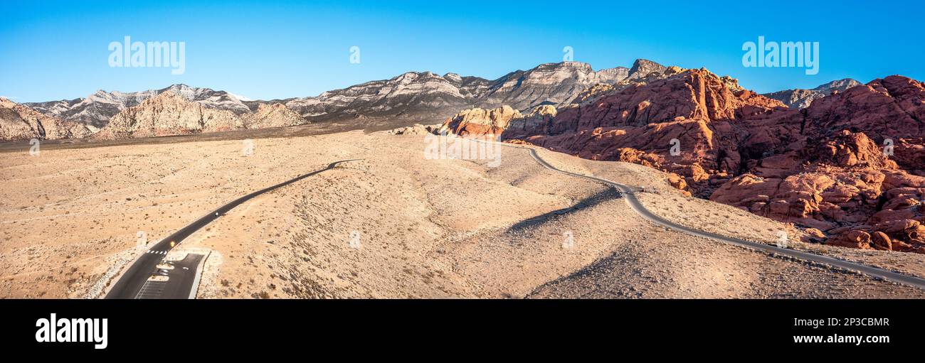 Red Rock Canyon in Las Vegas Nevada shows a lone, remote road along the vibrant mountainside where hiking activity is common. Stock Photo