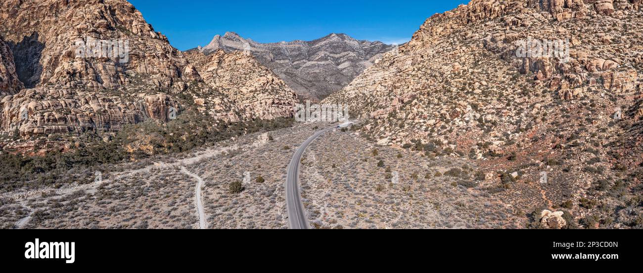 Red Rock Canyon in Las Vegas Nevada shows a lone, remote road along the vibrant mountainside where hiking activity is common. Stock Photo