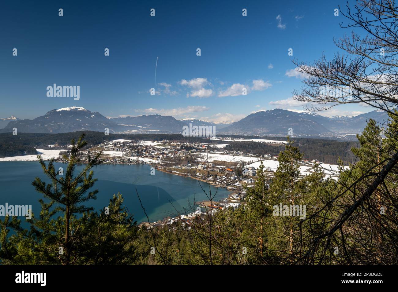The famous turquoise waters of the tranquil Lake Faaker See, surrounded by pine forests and snow capped mountains of the Austrian Salzkammergut Stock Photo