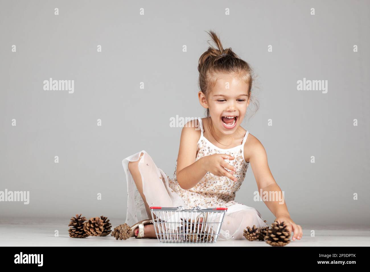 little caucasian girl playing with pinecones Stock Photo - Alamy