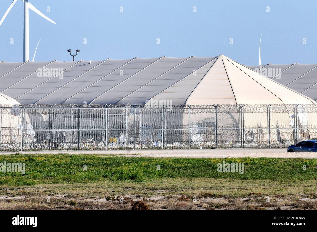 Trash has built up against the inside of the prison fence at the