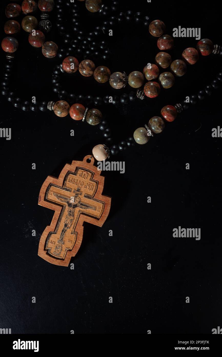 christian crucifix and rosary beads on abstract grey background