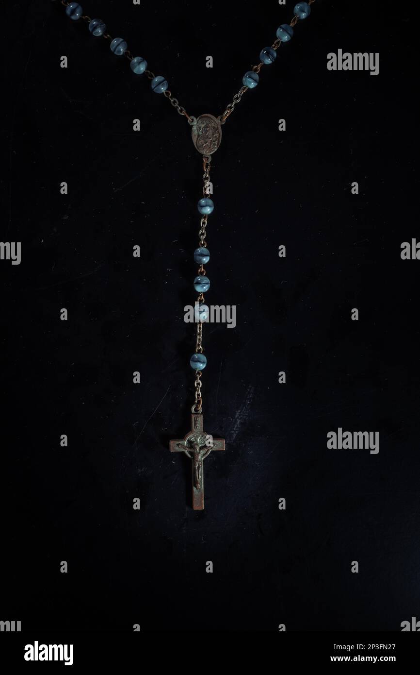 christian crucifix and rosary beads on abstract grey background