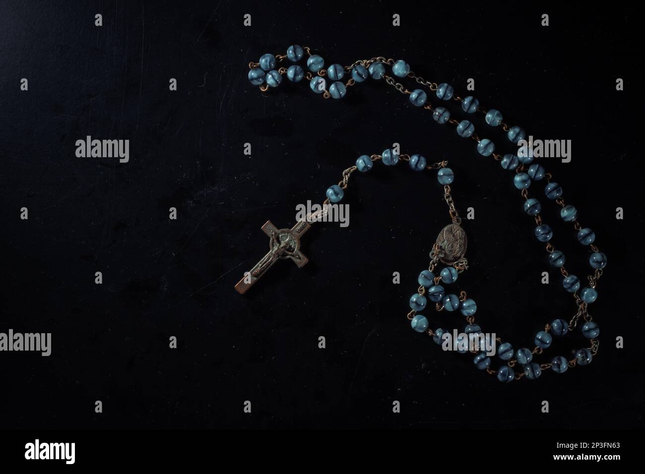 christian crucifix and rosary beads on abstract grey background