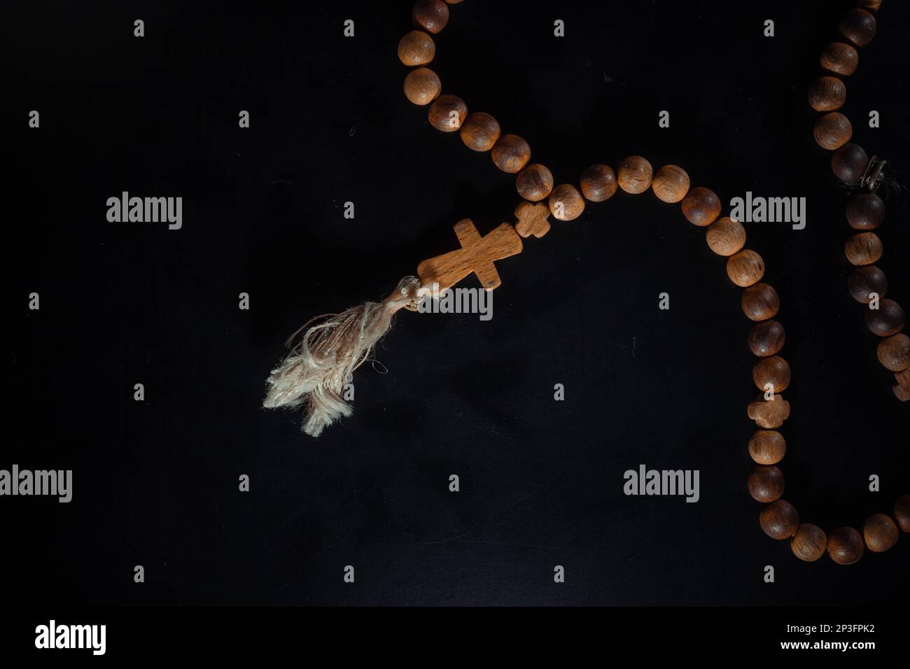 christian crucifix and rosary beads on abstract grey background