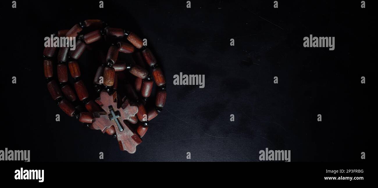 christian crucifix and rosary beads on abstract grey background