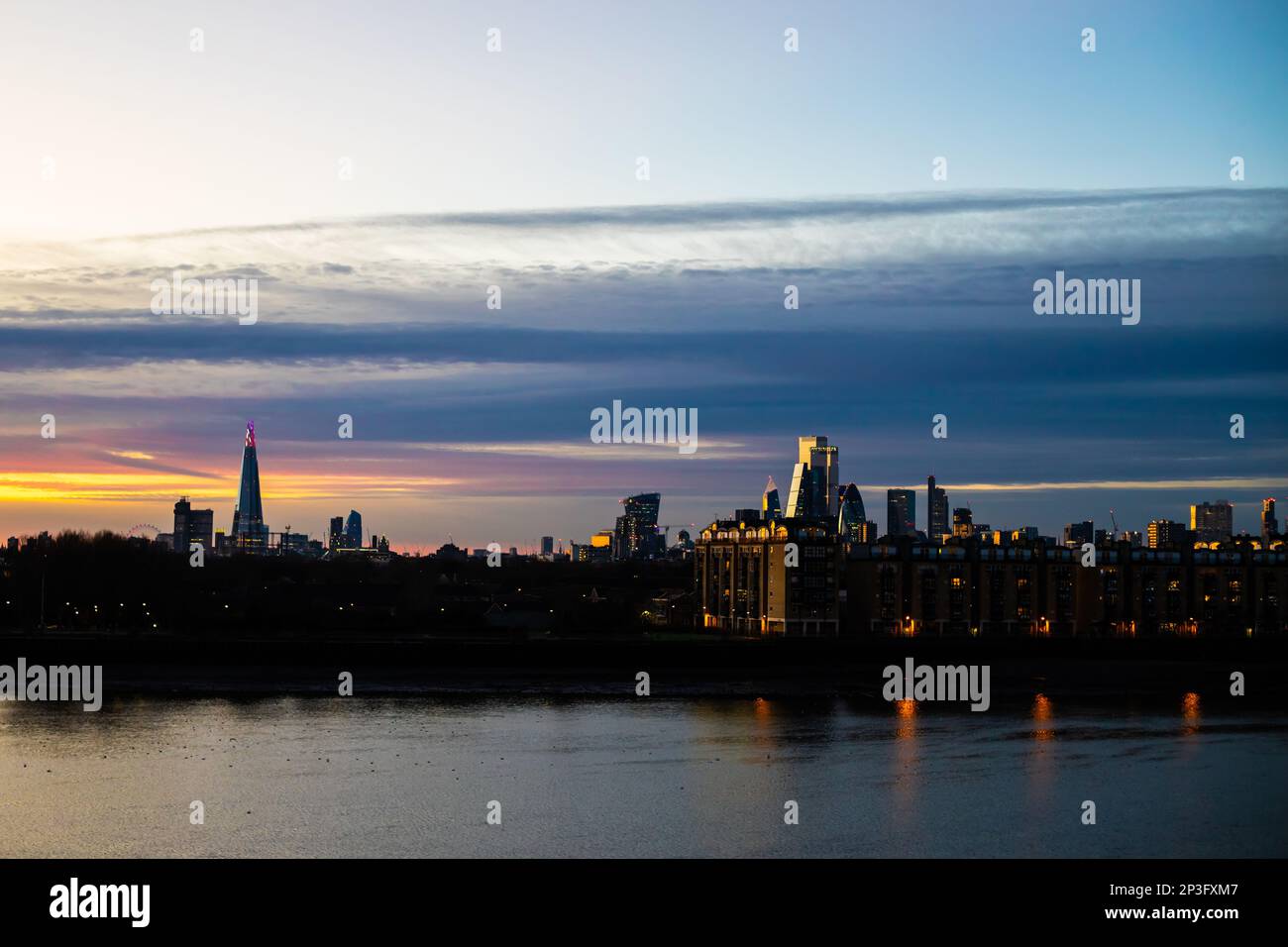 Sunset over the City of London and the Thames on a still day. The setting sun casts a beautiful twilight glow onto the buildings. Stock Photo
