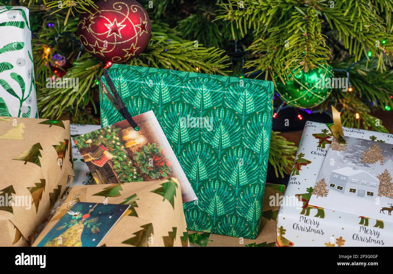 A close up of a pile of wrapped Christmas presents lying under the Christmas tree. They're wrapped in different patterned wrapping papers. Stock Photo