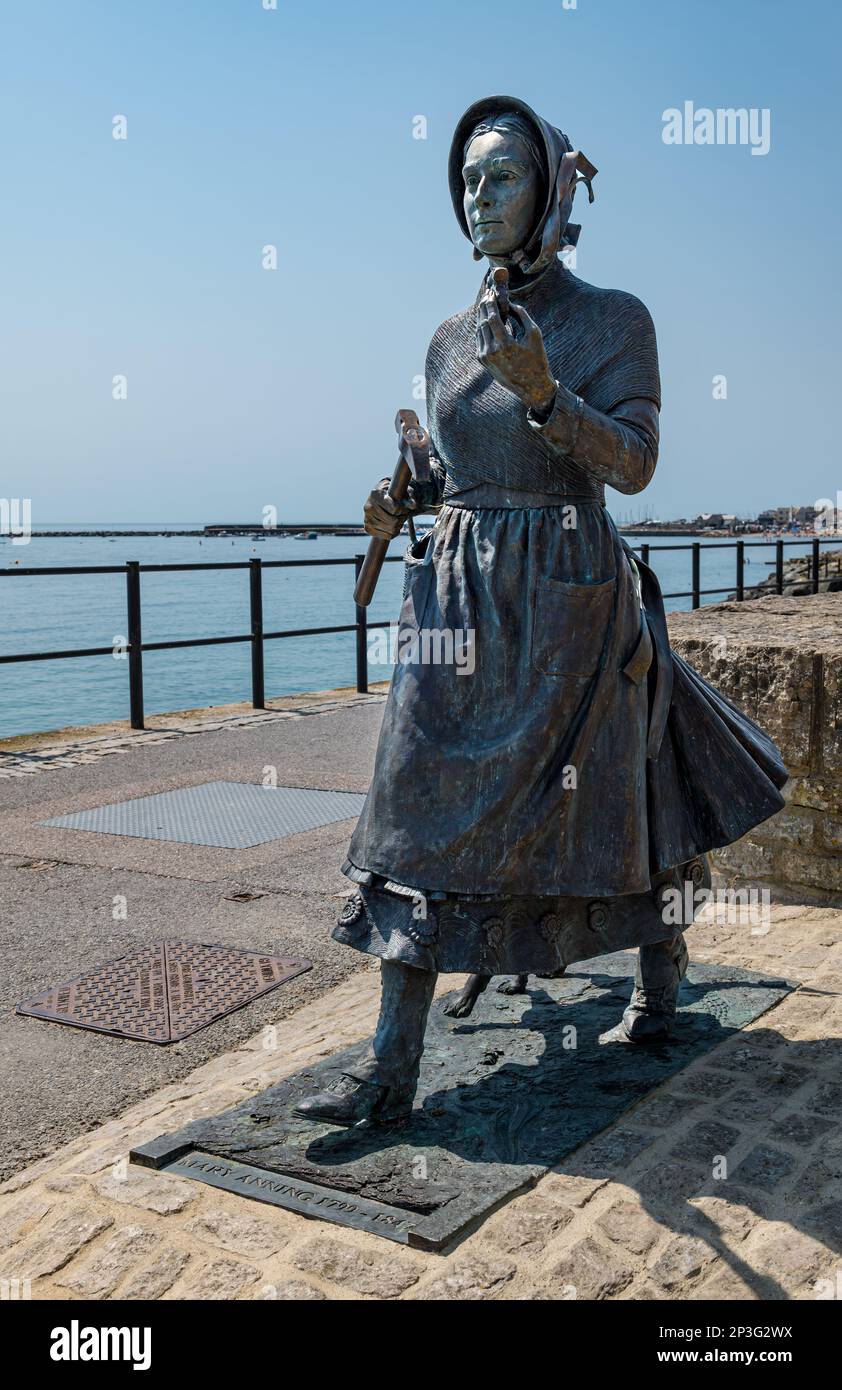 Bronze sculpture of geologist Mary Anning holding a fossil on Jurassic Coast, Lyme Regis, Dorset, England, UK Stock Photo