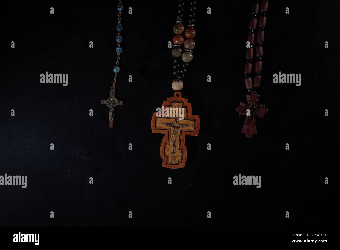 christian crucifix and rosary beads on abstract grey background