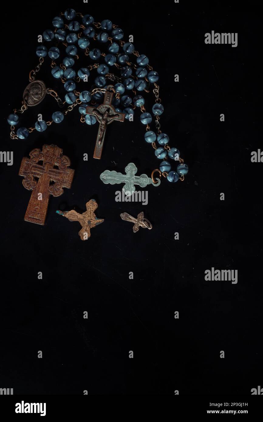 christian crucifix and rosary beads on abstract grey background