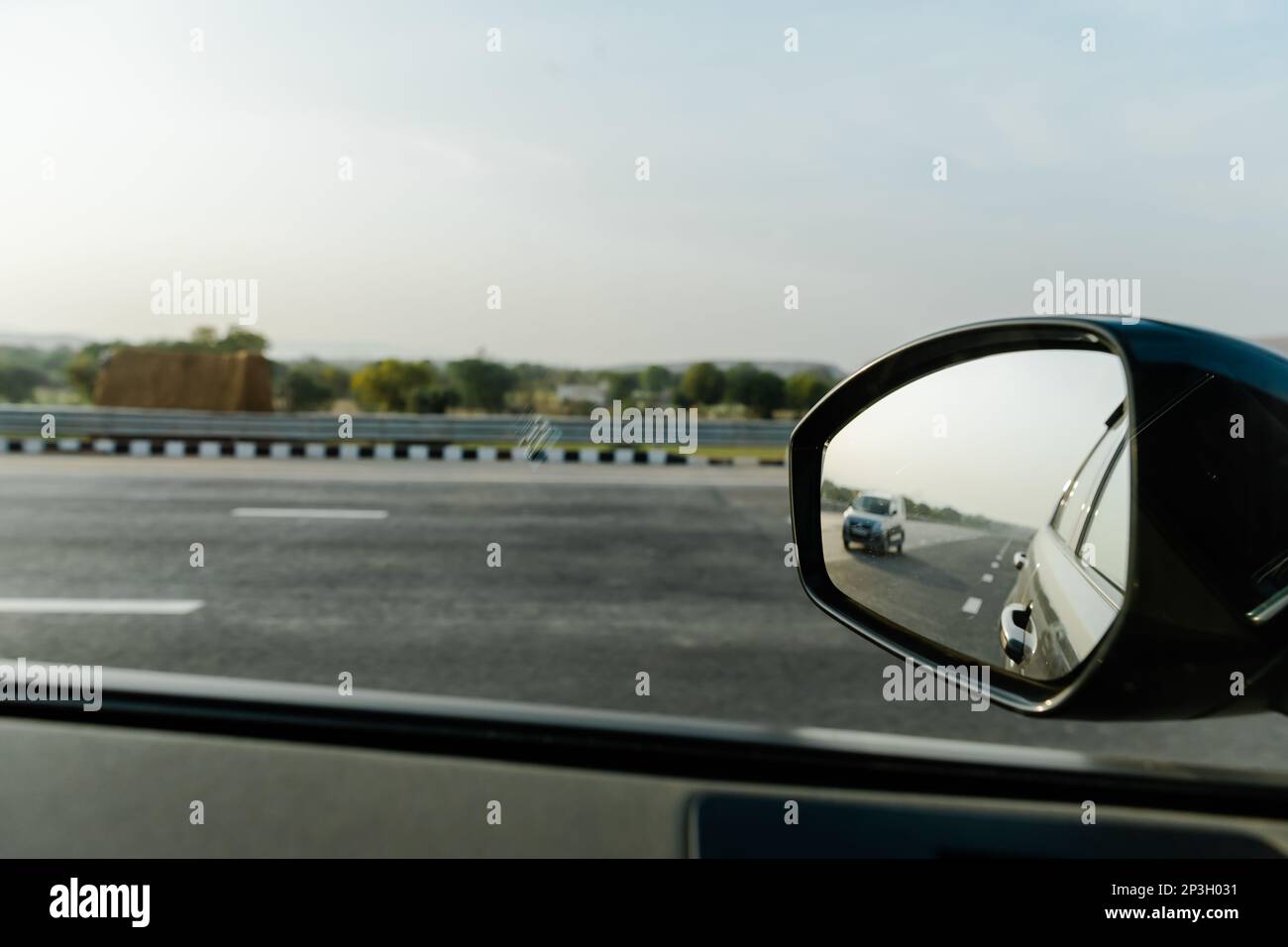 A closeup of a car side view mirror, positioned in the foreground