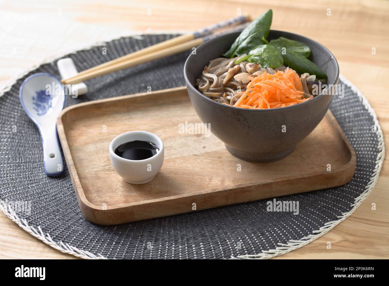 Shiitake mushrooms and soba noodle soup with carrot, spinach, and soy sauce on a wooden tray Stock Photo