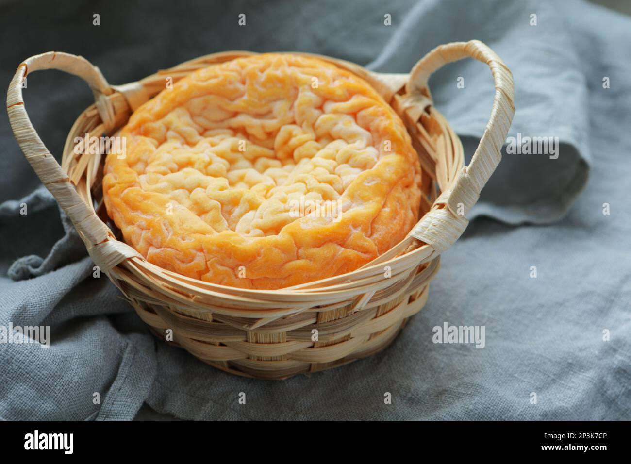 Langres cheese in a basket on a gray linen Stock Photo