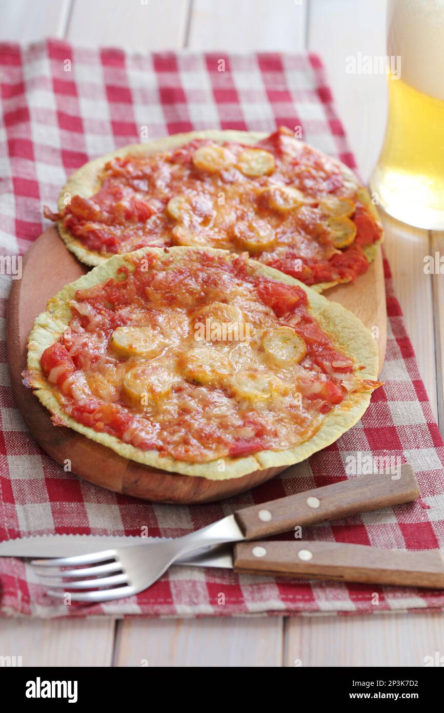 Sausage and tomatoes tortilla pizzas on a wooden board served with light beer Stock Photo