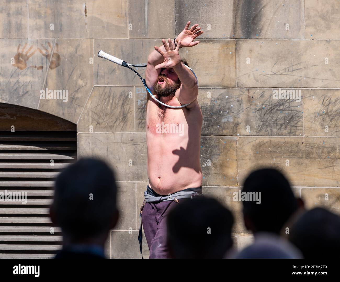 Street entertainer contortionist performing during festival with a tennis racquet, Royal Mile, Edinburgh, Scotland, UK Stock Photo